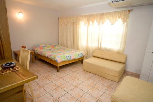 a bedroom with a bed and a chair and a window at Cool Running Apartments in Saint Georgeʼs