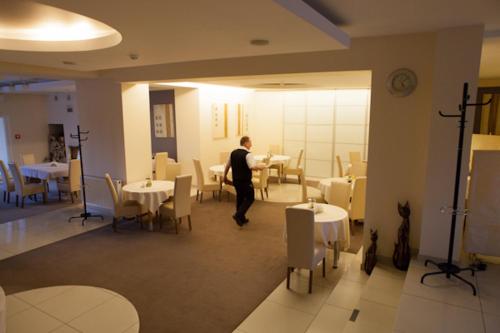 a man standing in a dining room with tables at Hotel Dodo in Biłgoraj