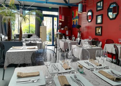 un restaurant avec des tables et des chaises blanches et des murs rouges dans l'établissement Logis Au Canard Gourmand, à Samatan