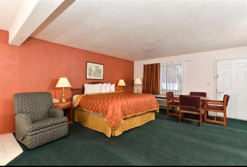 ein Hotelzimmer mit einem Bett, einem Schreibtisch und einem Stuhl in der Unterkunft Travel Inn & Suite in Springerville