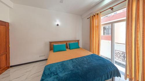 1 dormitorio con cama con sábanas azules y ventana en Ocean Breeze Apartment Colombo, en Colombo