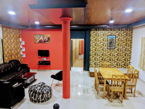 a dining room with a table and a red wall at Ivy Orchids Villa - Lonavala in Lonavala