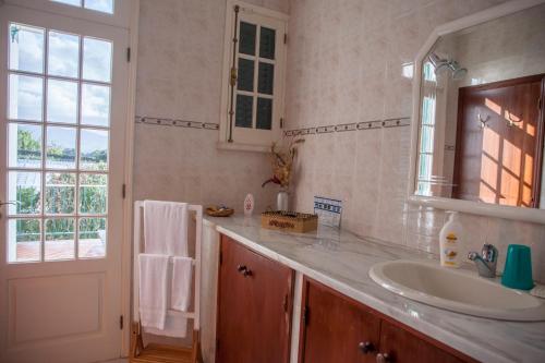 uma casa de banho com um lavatório, um espelho e uma janela em Quinta das Bolas em Ponta Delgada