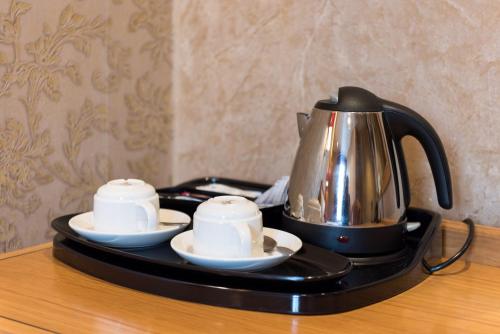 a tea kettle and two cups on a tray on a table at The Montana Hotel in London