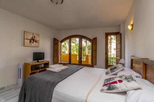 een slaapkamer met een groot wit bed en een tv bij Apartmento Carla Punta Prima in Torrevieja