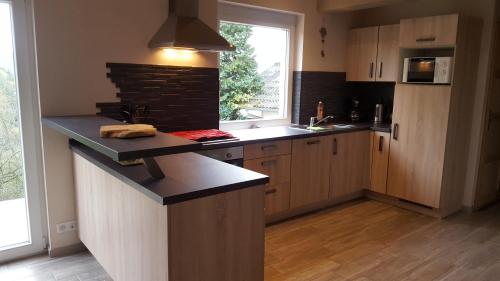 a kitchen with wooden cabinets and a counter top at Gîte ESPERANZA SPA et SAUNA in Hazelbourg