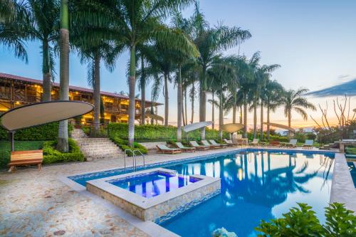 a swimming pool with palm trees and a building at Hotel Casa San Carlos Lodge Pereira in Pereira