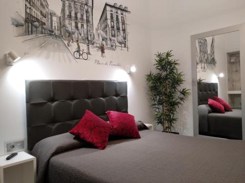 a bedroom with a bed with red pillows on it at Hostal Lauria in Madrid