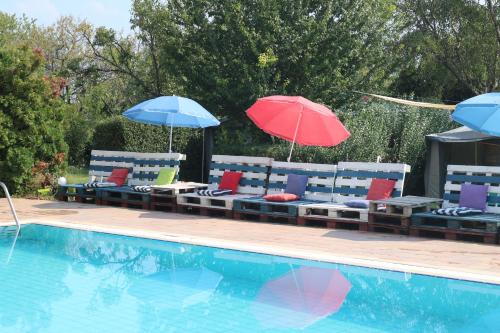 two umbrellas and lounge chairs next to a swimming pool at Mandel Camping in Paloznak
