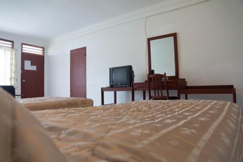 a bedroom with a bed and a desk and a tv at Toledo Inn in Tuk Tuk