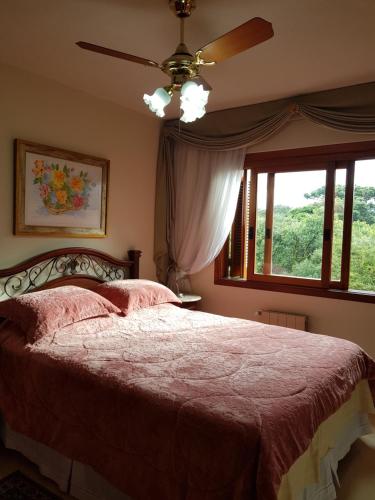 Schlafzimmer mit einem Bett, einem Deckenventilator und einem Fenster in der Unterkunft Apartamento Monte Bianco in Gramado