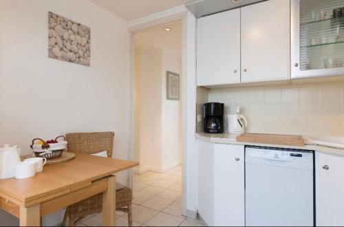 une cuisine avec des armoires blanches et une table en bois dans l'établissement Cap View, à Antibes