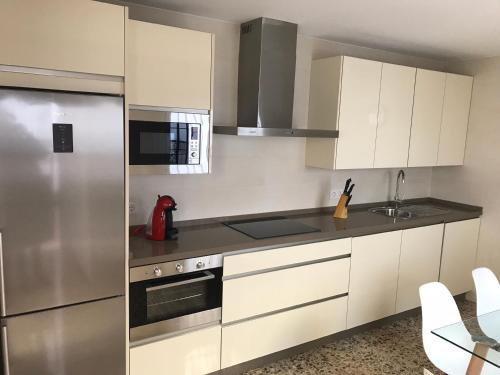 a kitchen with white cabinets and a stainless steel refrigerator at Casa patio ribera de córdoba in Córdoba