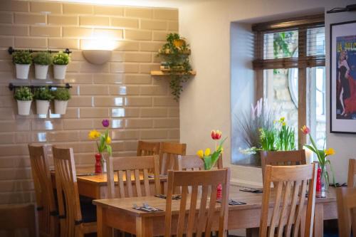 a dining room with a table and chairs and flowers at Chester House Hotel in Bourton on the Water