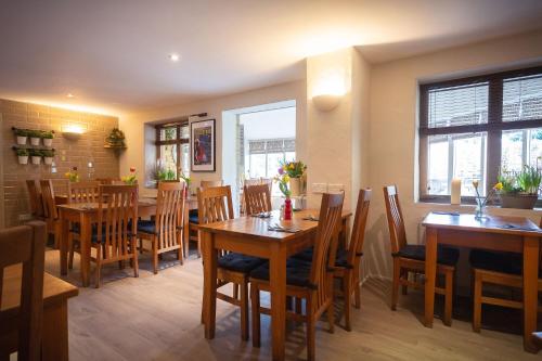 uma sala de jantar com mesas e cadeiras de madeira em Chester House Hotel em Bourton on the Water