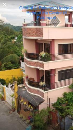 a tall pink building with a balcony and a store at Palompon lodge in Palompon