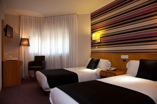 una habitación de hotel con 2 camas y una silla en Hotel Palacio de Cristal en Burela de Cabo