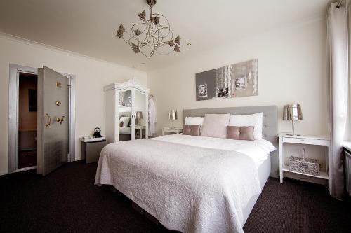 a white bedroom with a large bed and a chandelier at Villa BBB in Oosterhout