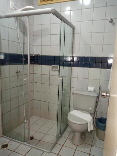 a bathroom with a toilet and a glass shower at Hotel Nacional Service in Goiânia