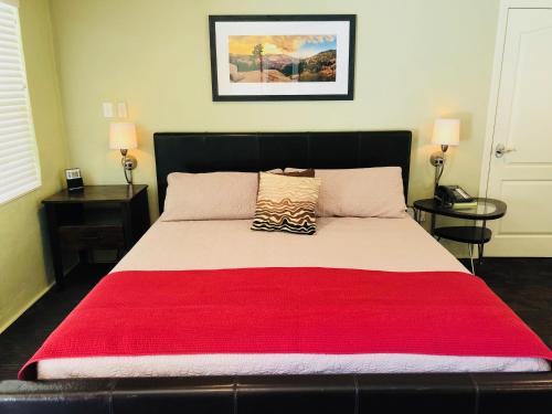 a bedroom with a large bed with a red blanket at Queen's Inn By The River in Oakhurst