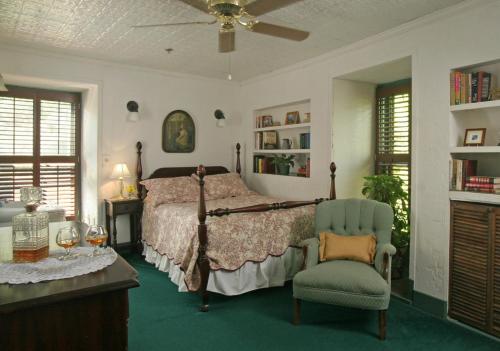 a bedroom with a bed and a chair and a fan at St. Francis Inn - Saint Augustine in Saint Augustine