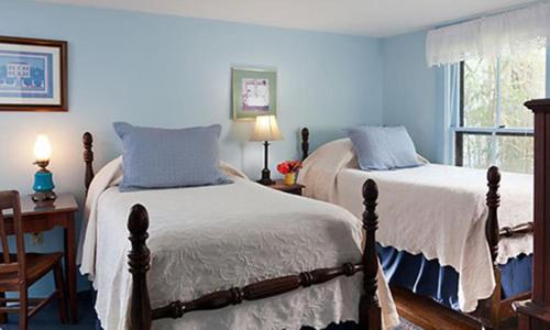 a bedroom with two beds and a desk and a window at St. Francis Inn - Saint Augustine in Saint Augustine
