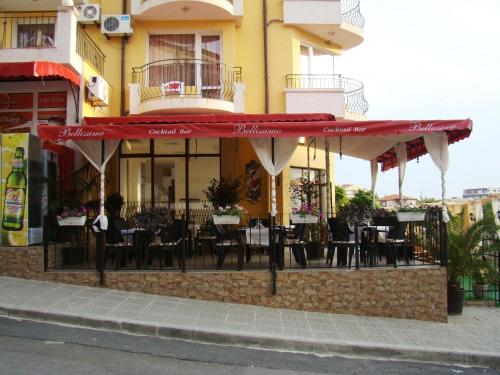 a restaurant with red umbrellas in front of a building at Hotel Bellisimo in Lozenets