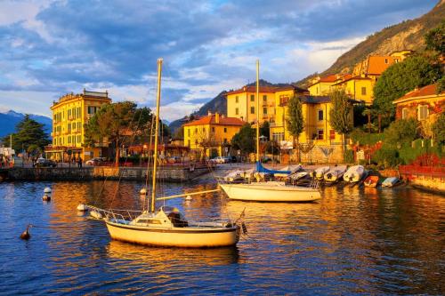 two boats are docked in a body of water with buildings at Da Mara Lago Di Como in Sormano