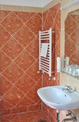 a bathroom with a sink and a tiled wall at Classic Hotel in Budapest