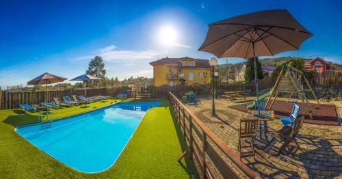 einen Pool mit Stühlen und einem Sonnenschirm in der Unterkunft Apartamentos Cudillero in Cudillero