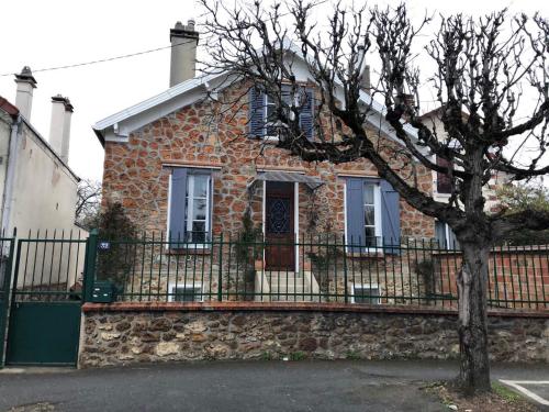 uma casa de tijolos com uma cerca e uma árvore em Lalanie em Savigny-sur-Orge