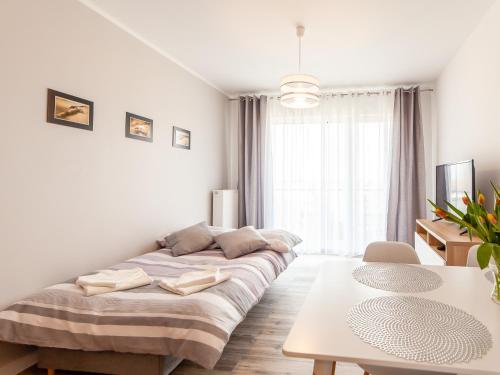 biały pokój z łóżkiem i stołem w obiekcie Apartament Rybacka 12A/68, Kołobrzeg w Kołobrzegu