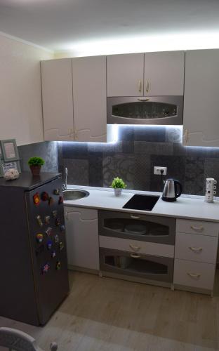 a kitchen with white cabinets and a black refrigerator at Apartman Bloom in Bar