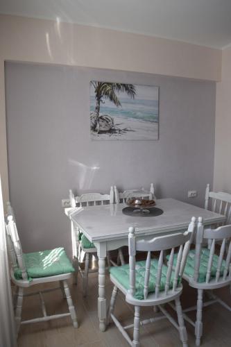 a white table and chairs with a table and a palm tree at Apartman Bloom in Bar