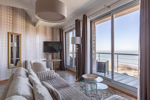 a living room with a couch and a large window at Domaine du Grand Bec in Villerville
