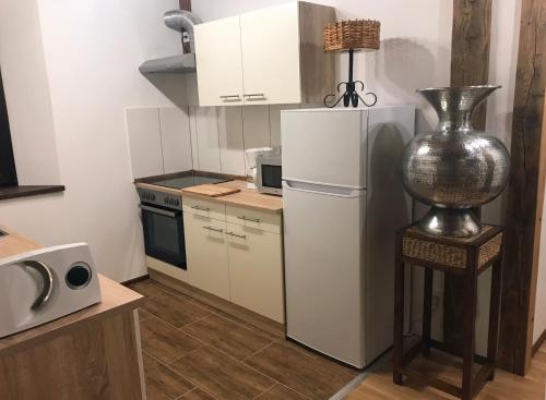 a small kitchen with a refrigerator and a lamp on a stool at Ferienwohnung PENZLIN im Rittergut Leppersdorf bei Dresden in Wachau