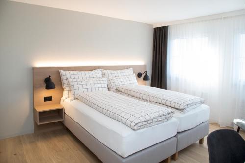 ein weißes Bett in einem Schlafzimmer mit einem Fenster in der Unterkunft Forum - das Business & Lifestylehotel in Widnau