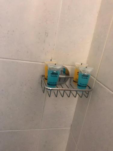 a shelf in a bathroom with three bottles on it at Pinpoint Rooms in Mesolongion