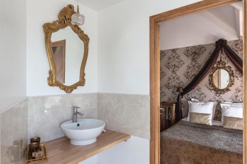 a bathroom with a sink and a bed with a mirror at Domaine du Grand Bec in Villerville