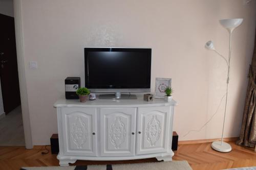 a tv on a white cabinet in a living room at Apartman Bloom in Bar