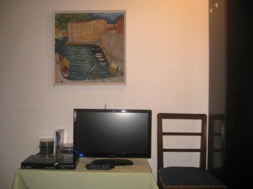 a computer monitor sitting on a table with a chair at Nikolina Rooms in Dubrovnik