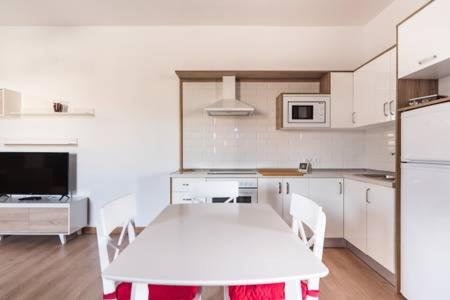 a white kitchen with a white table and chairs at Casa de Los Alberconcillos in Agüimes