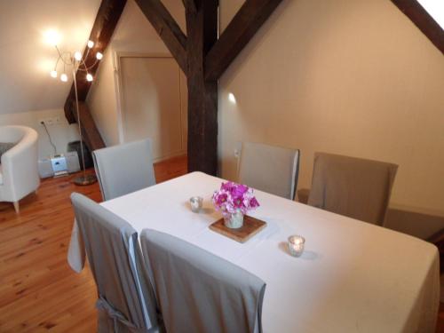 a white table with chairs and a vase of flowers on it at Le Clos Audy près de Chambord in Huisseau-sur-Cosson