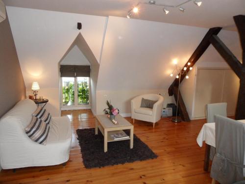 a living room with a white couch and a table at Le Clos Audy près de Chambord in Huisseau-sur-Cosson