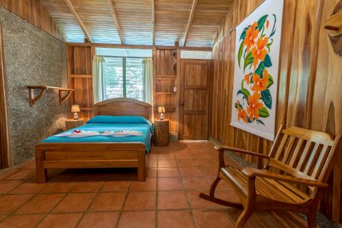 a bedroom with a bed and a chair in a room at La Cusinga Lodge in Uvita