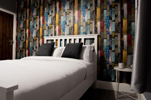 a bedroom with a white bed and a colorful wallpaper at REM Hotel in Manchester
