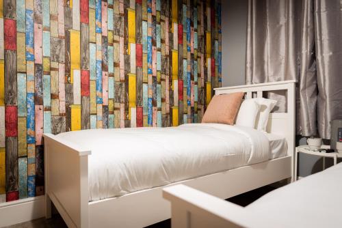 a bedroom with a white bed and a colorful wall at REM Hotel in Manchester