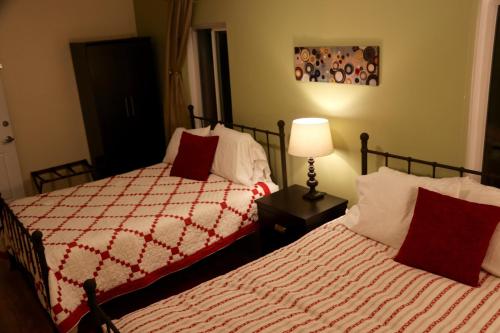 a bedroom with two beds with red pillows and a lamp at Mancos Inn in Mancos