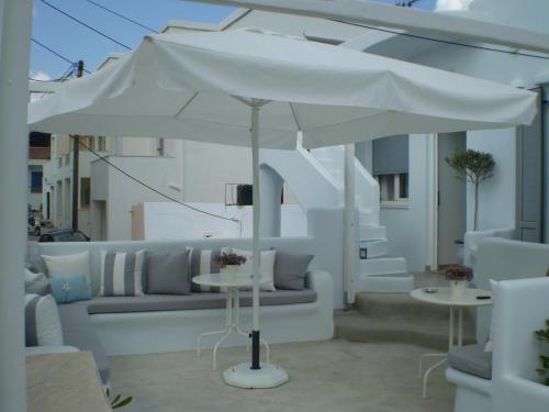 a white umbrella on a patio with a couch and tables at Eleftheria Veloudiou in Tinos Town