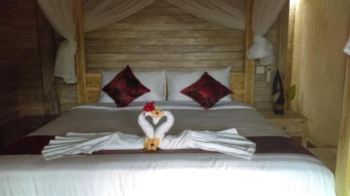 a woman dressed in white is sitting on a bed at La Gautch Bungalow in Nusa Lembongan